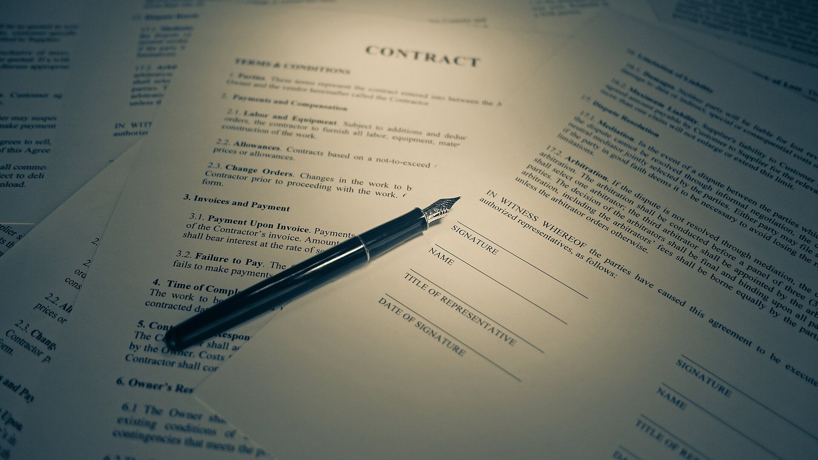 A fountain pen resting on a printed contract with signature lines