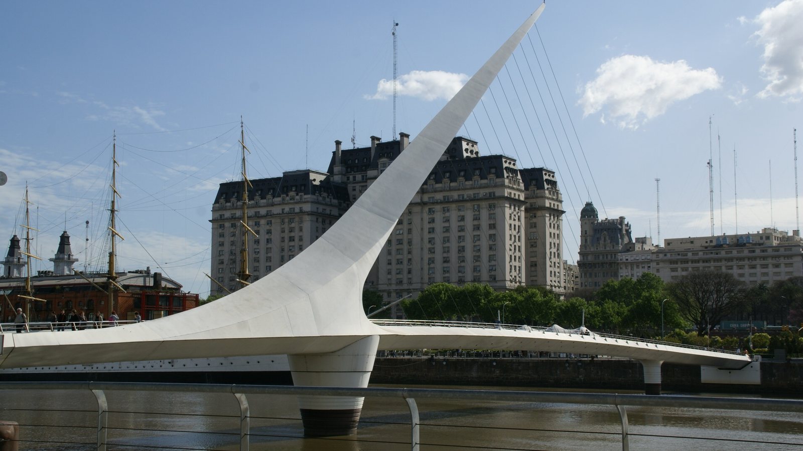 The white Puente de la Mujer footbridge over the dock at Puerto Madero in Buenos Aires, with an old sailing ship and large office buildings behind