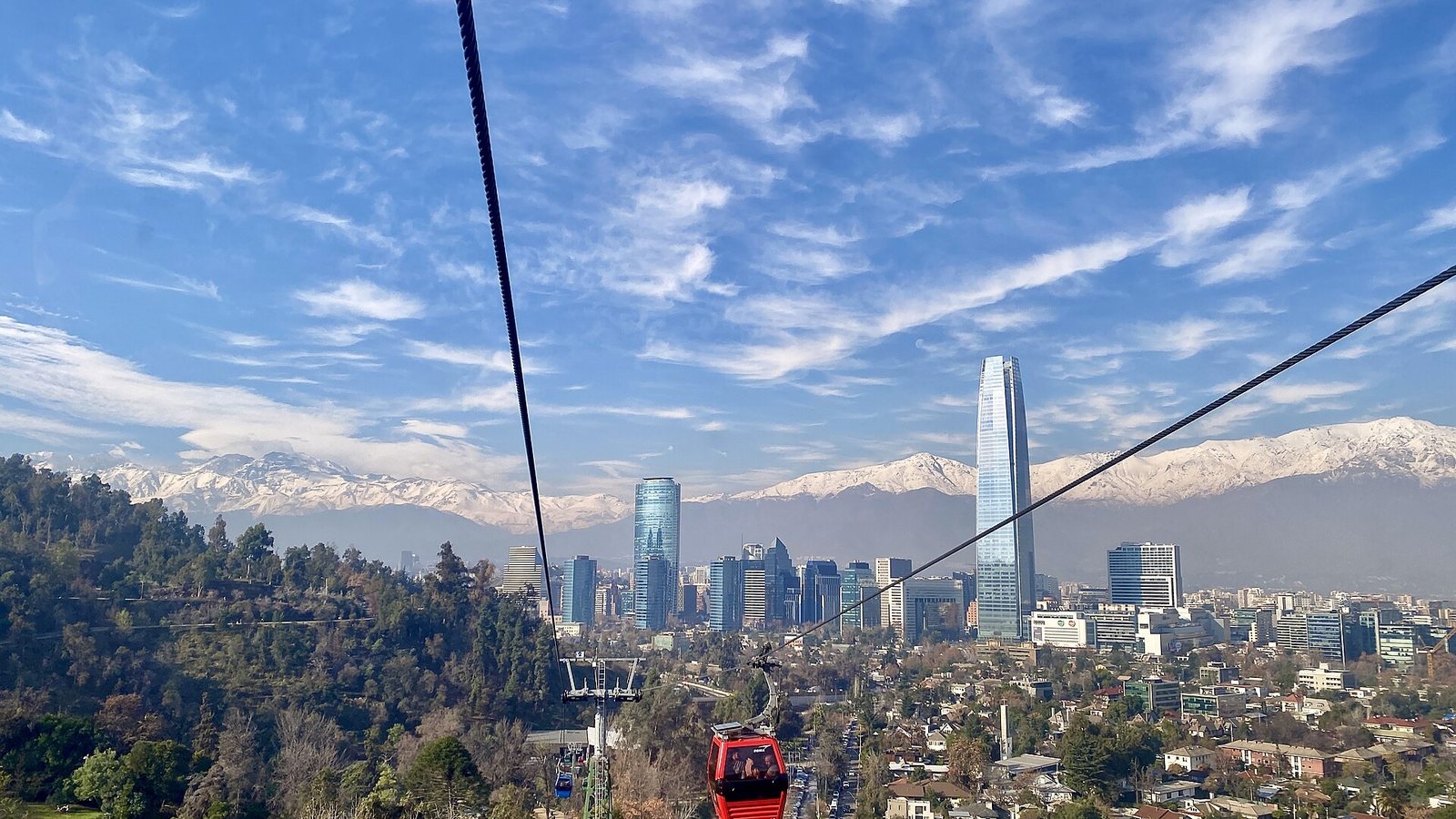 The towers of Santiago's business district with the snow-covered Andes behind, seen from the cable car on San Cristobal hill under a blue sky