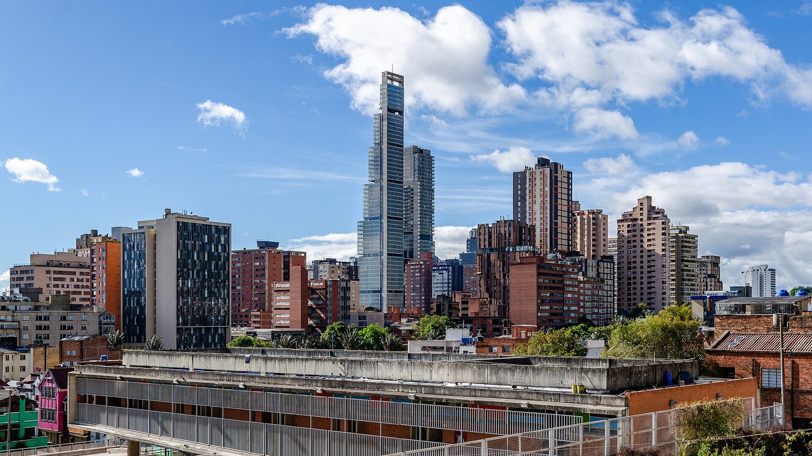 Office and residential towers in the Santa Fe district of central Bogotá under a blue sky with white clouds