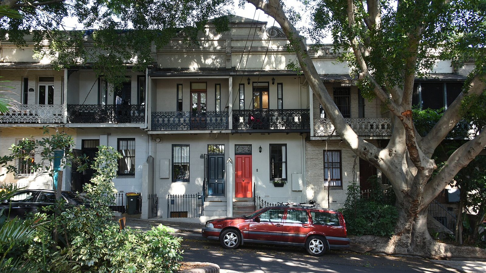 A row of two-storey terrace houses with iron-lace balconies on a tree-lined street in Paddington, Sydney
