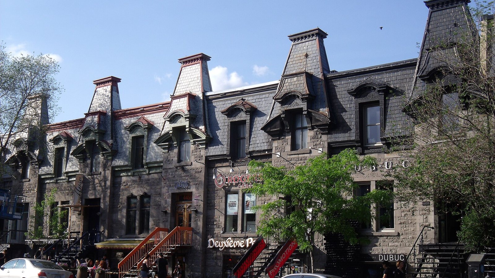 Stone row houses with mansard roofs and outdoor staircases on Saint-Denis Street in Montreal