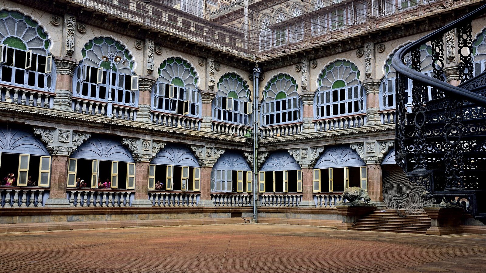 Courtyard of Mysore Palace with arched windows and a wrought-iron spiral staircase
