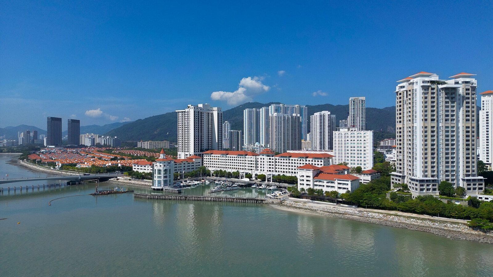 Seafront apartment towers and a marina at Tanjong Pinang in George Town, Penang, under a blue sky