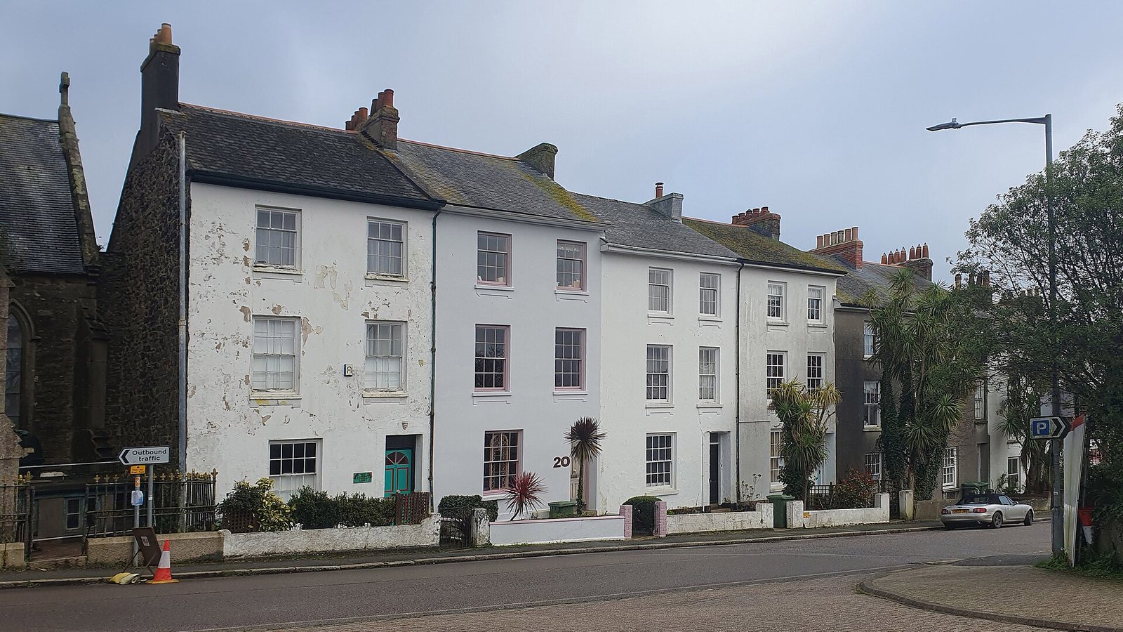 A row of white-painted terraced houses on a street in Penzance, Cornwall