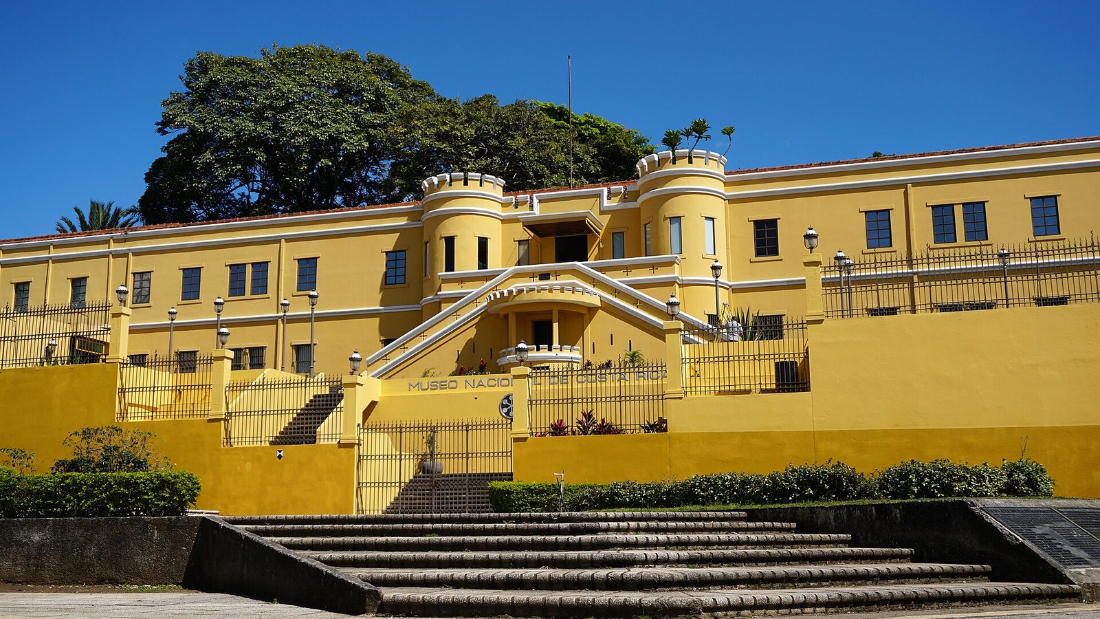 The yellow fortress-style building of the National Museum of Costa Rica in San José, with steps in front and a deep blue sky