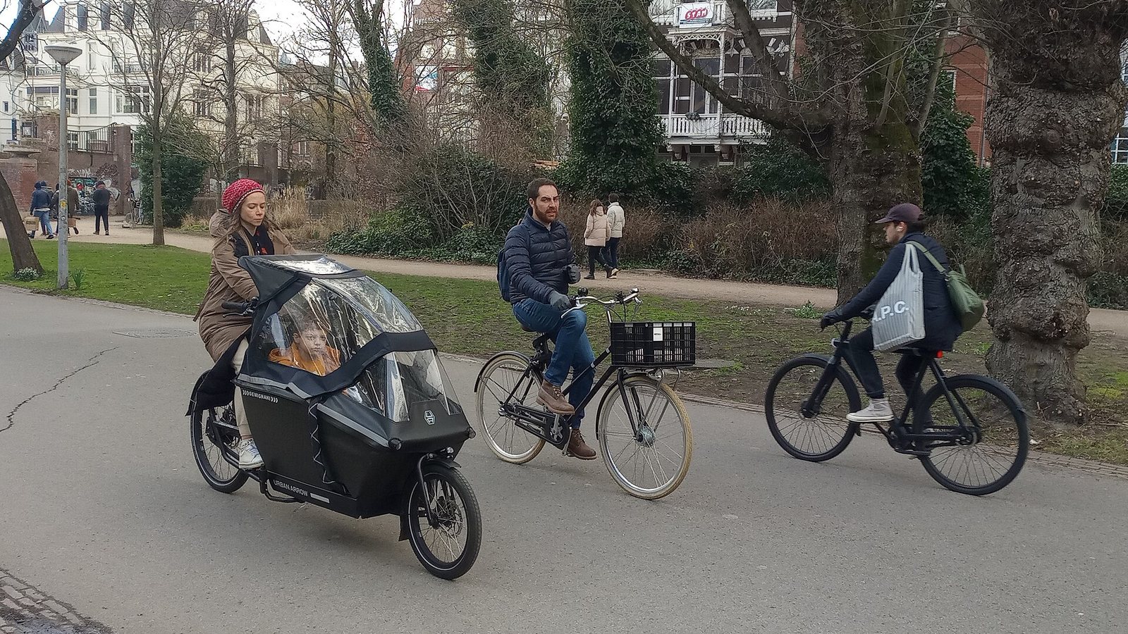 A parent with a child in a cargo bike and other cyclists in Vondelpark, Amsterdam
