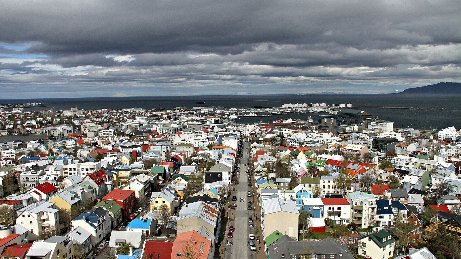 Colourful houses of central Reykjavík seen from above, stretching to the harbour and the sea under heavy grey clouds