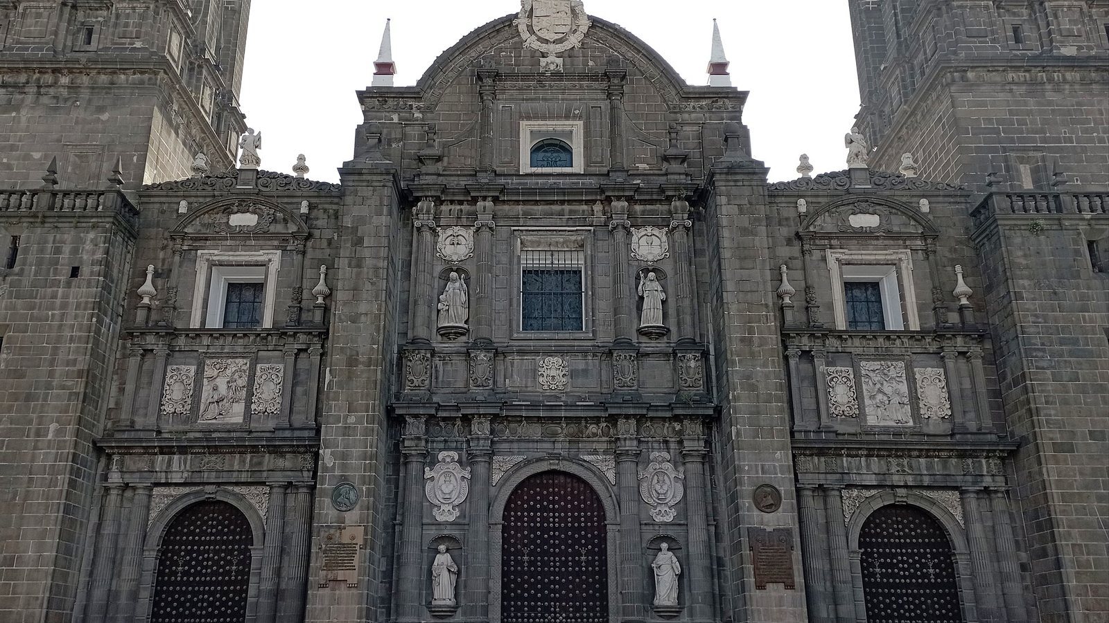 Carved stone façade of Puebla Cathedral in Mexico with its central portal and flanking towers