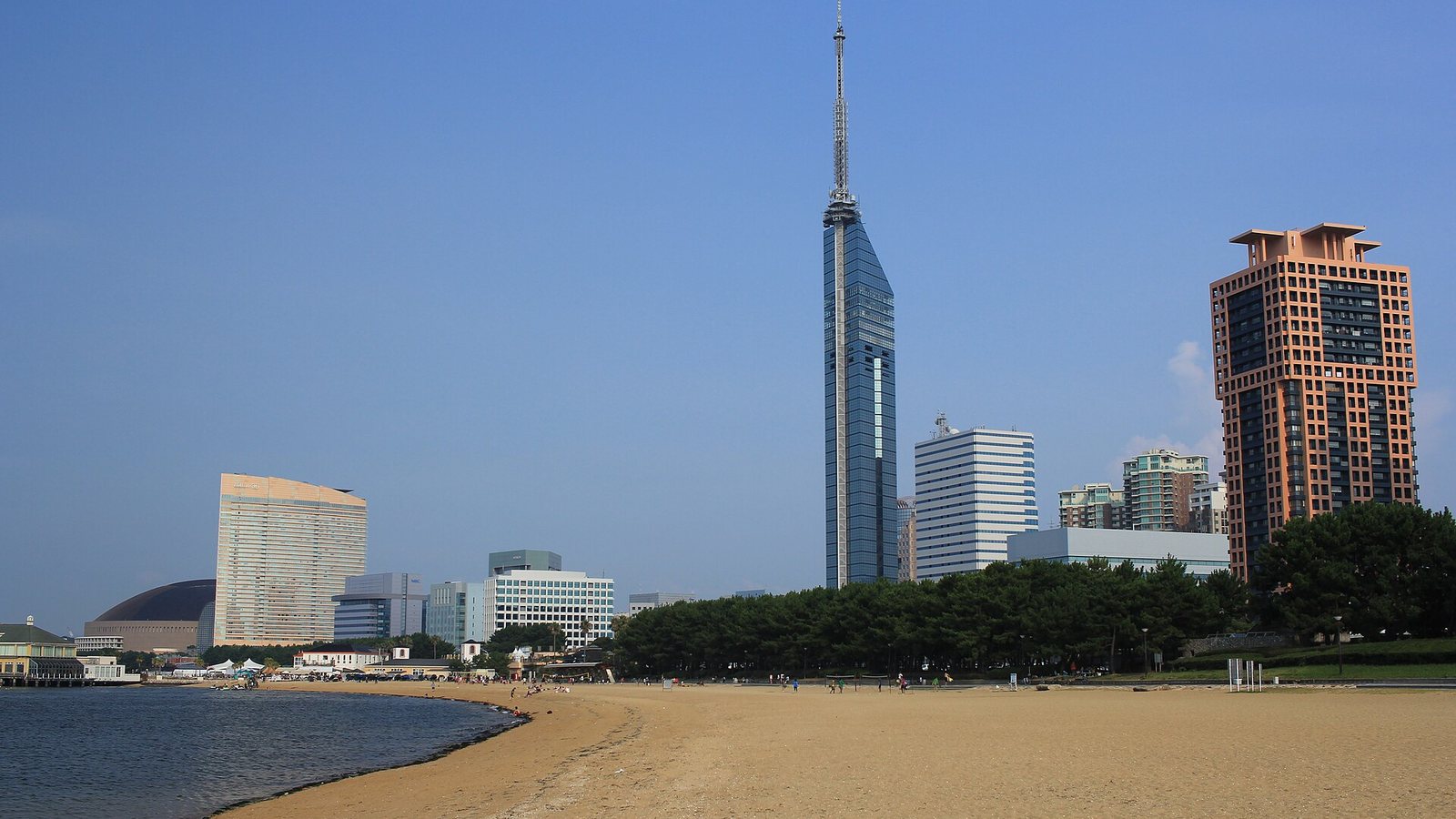 The sandy beach at Seaside Momochi in Fukuoka with Fukuoka Tower and waterfront buildings behind it under a clear blue sky