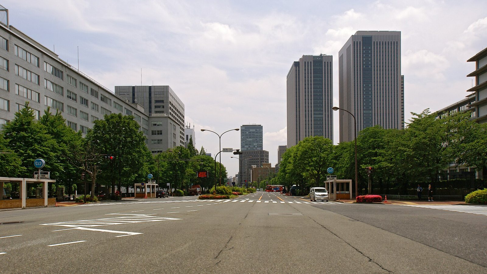 A wide tree-lined avenue running between ministry buildings and office towers in the Kasumigaseki government district of Tokyo