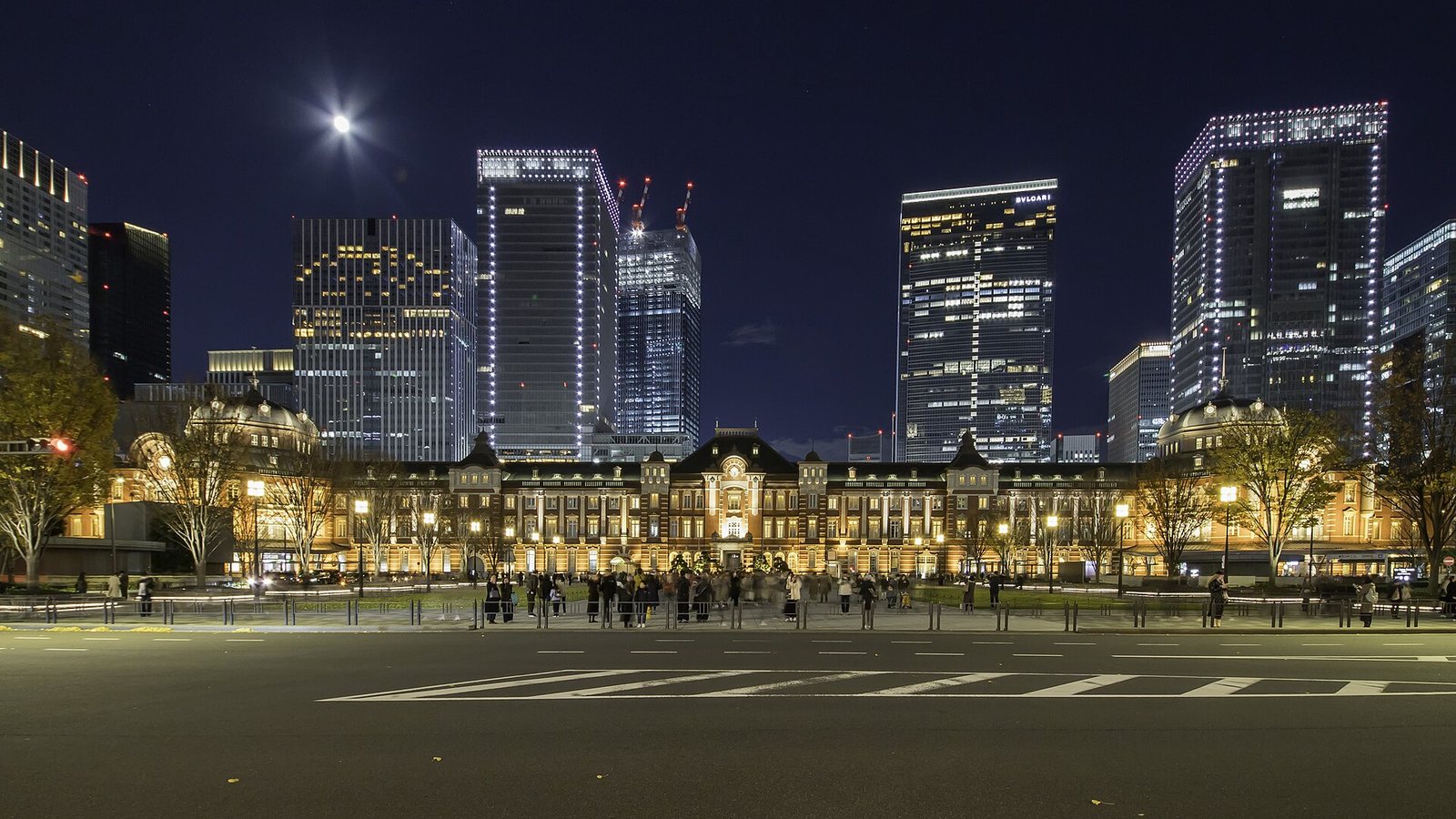 The red-brick Tokyo Station Marunouchi building lit up at night in front of office towers