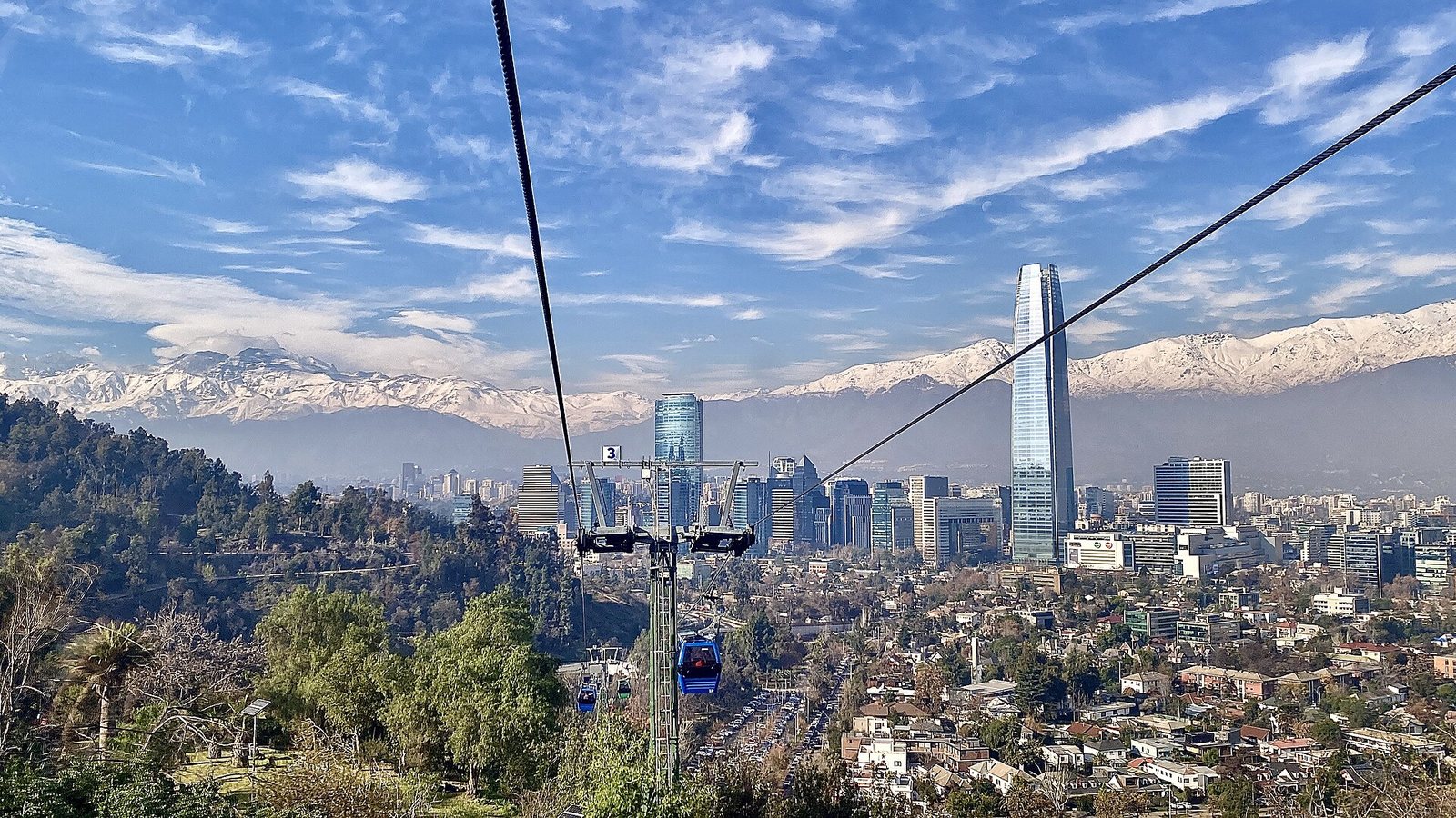 A cable car line running down San Cristobal hill towards the towers of Santiago, with the snow-covered Andes across the horizon under a blue sky