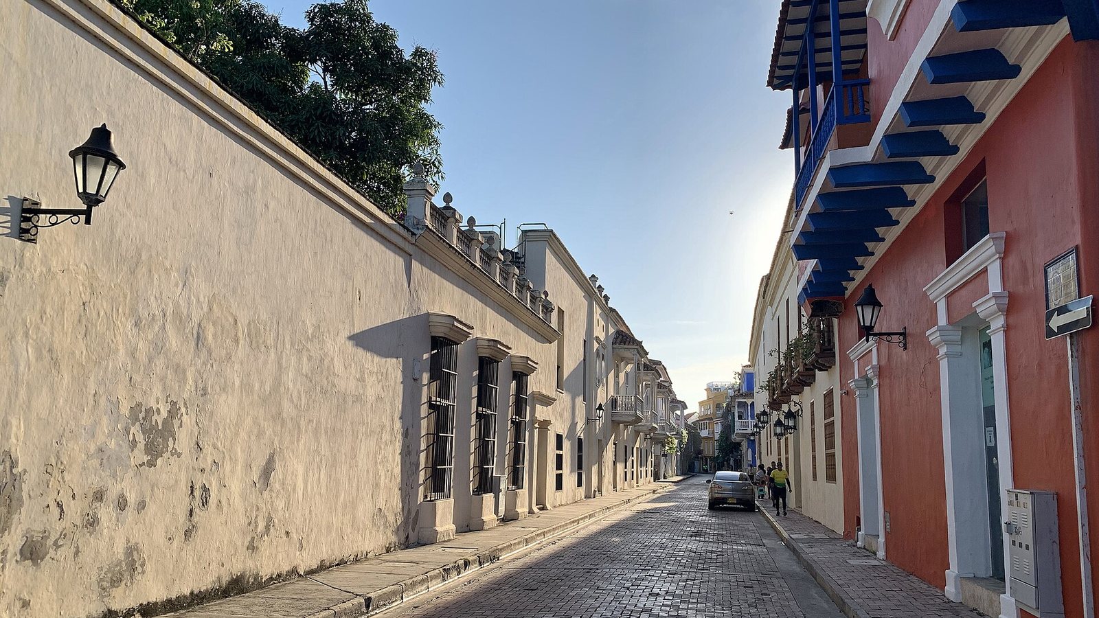 A cobbled street in the old town of Cartagena de Indias lined with colonial houses, wooden balconies and wall lanterns in afternoon light
