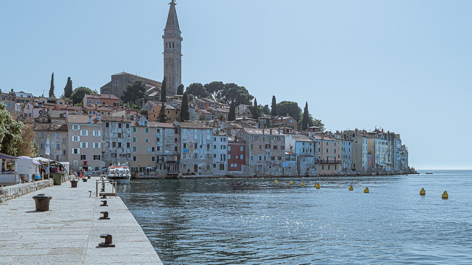 The old town of Rovinj on its peninsula, with pastel houses rising from the sea to the bell tower of the church of St Euphemia under a clear sky