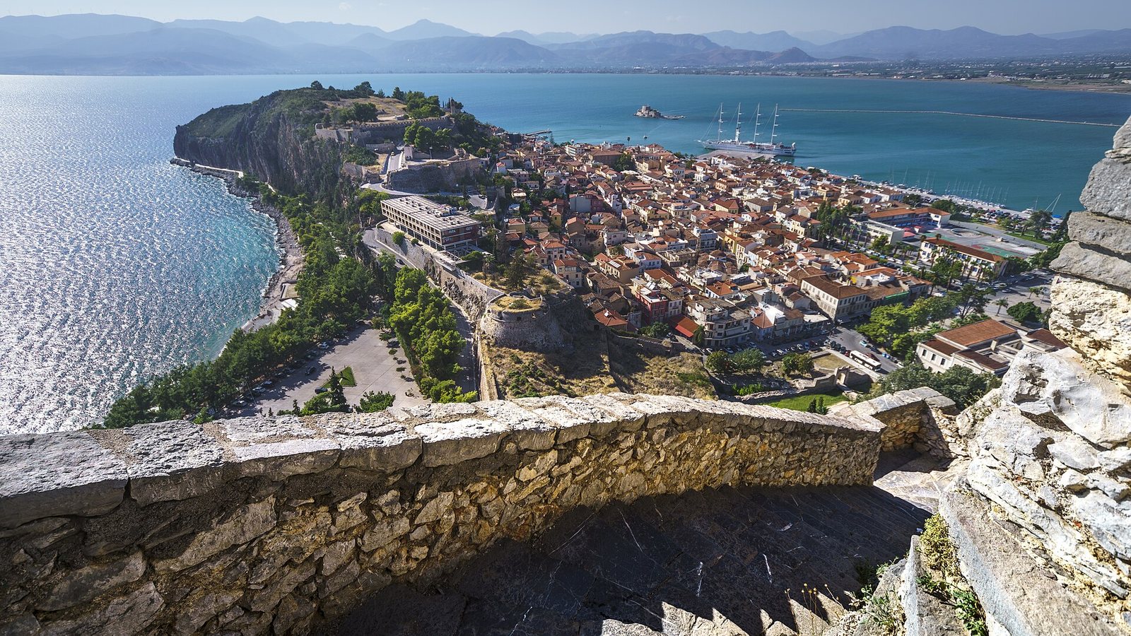 View from the Palamidi fortress over the red roofs of Nafplio, the Akronafplia headland, the harbour and the bay with mountains beyond