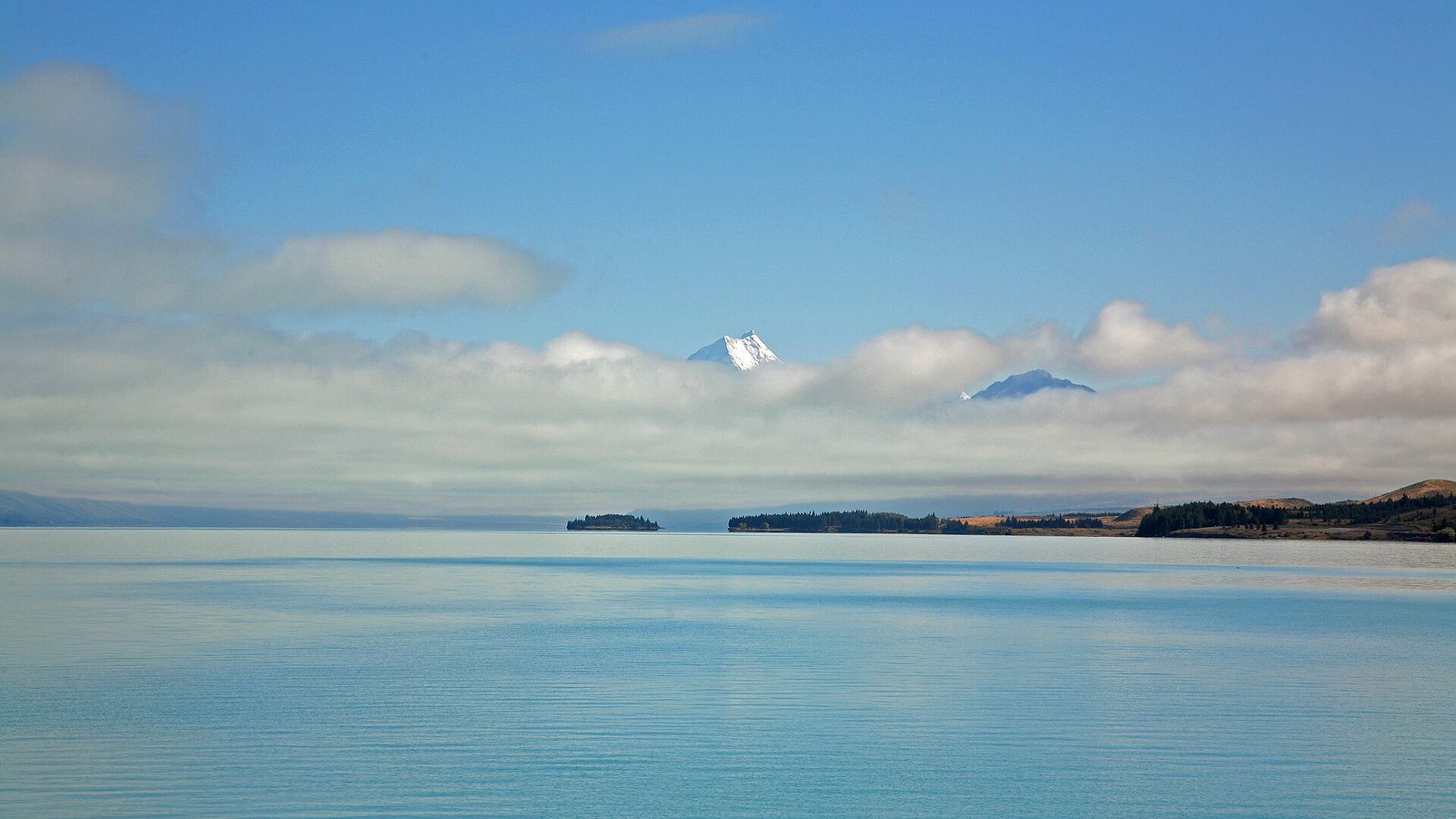 Lake Pukaki in New Zealand's South Island, with a snow-covered peak rising above low cloud