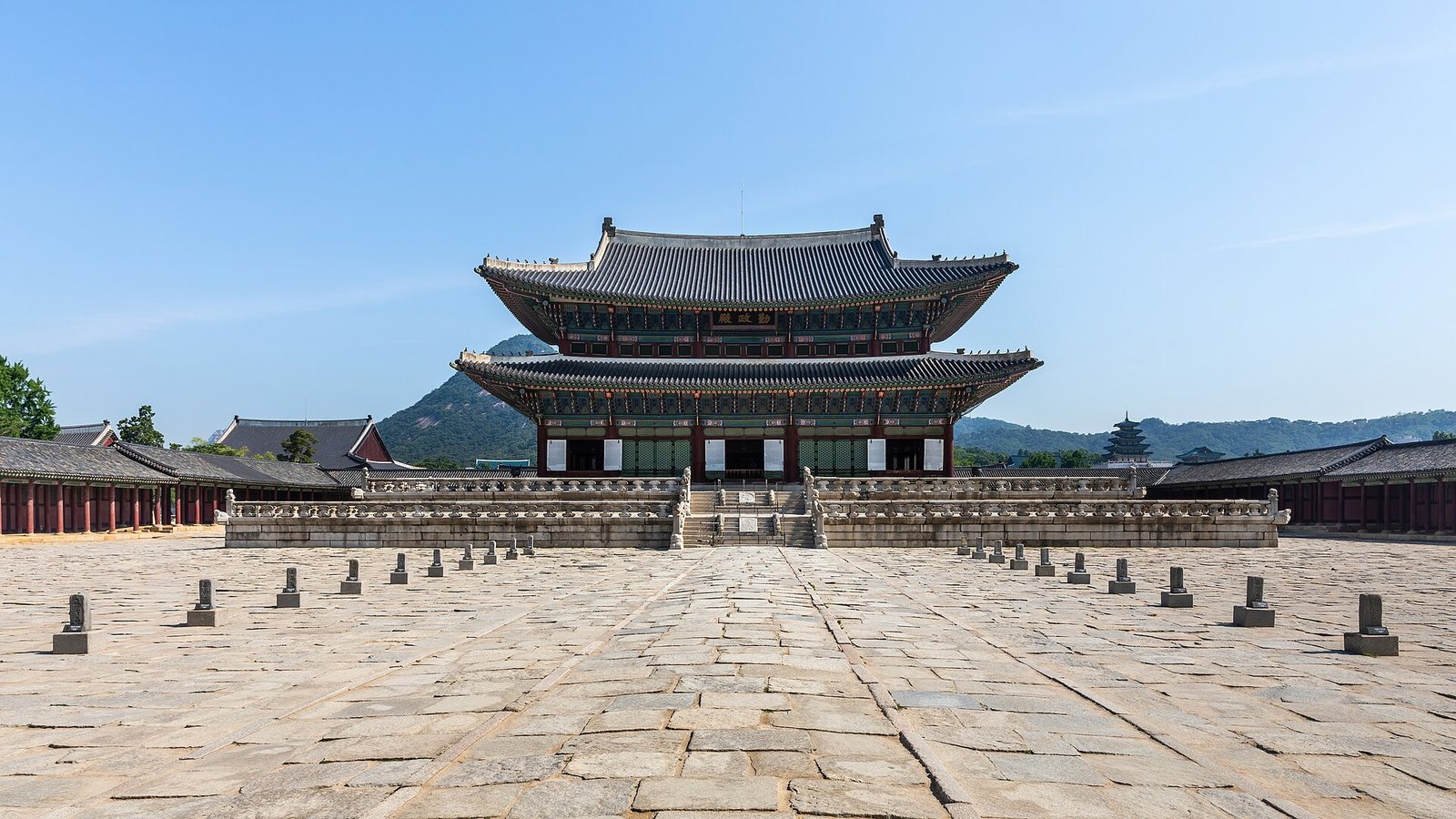 Geunjeongjeon, the throne hall of Gyeongbokgung Palace in Seoul, across its stone courtyard under a blue sky