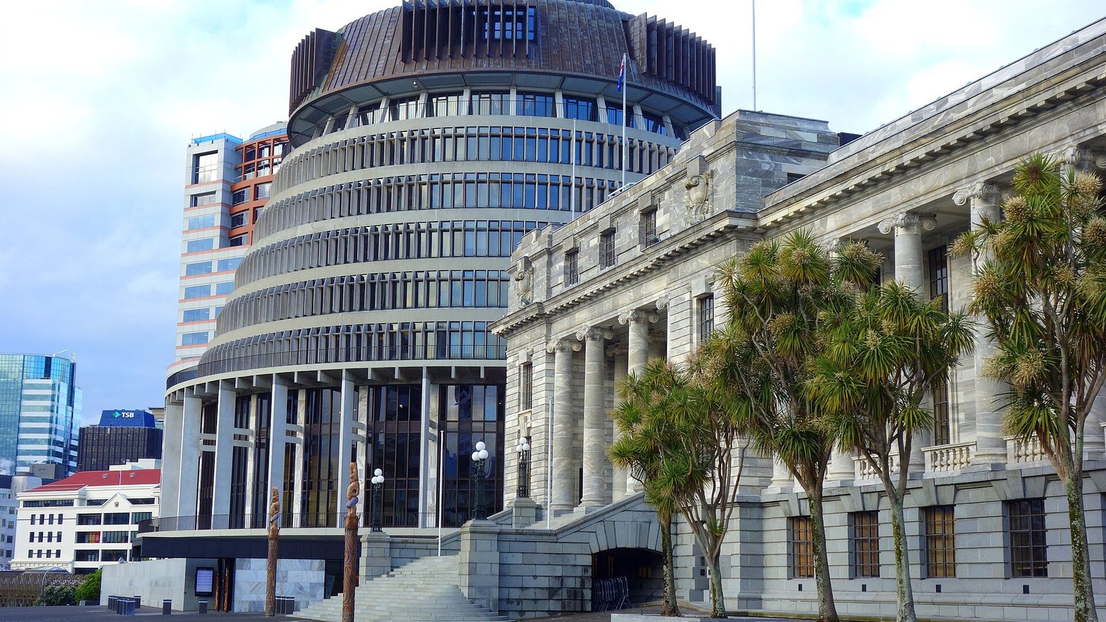 The Beehive and Parliament House in Wellington, New Zealand's parliament buildings, with cabbage trees in front