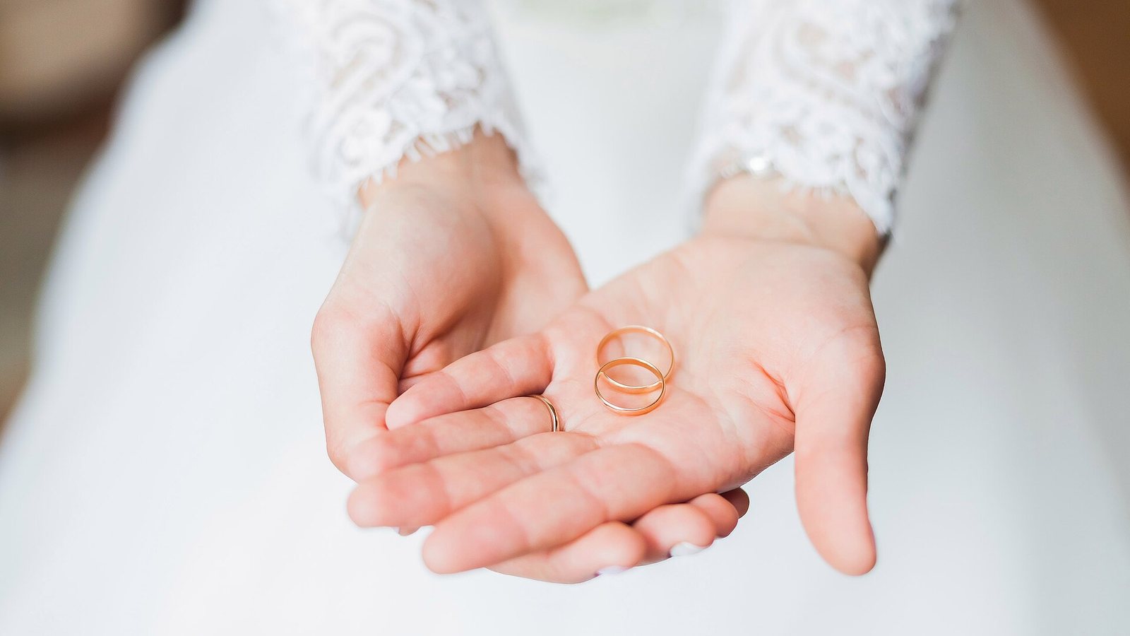 A bride holding two gold wedding rings in her open hands
