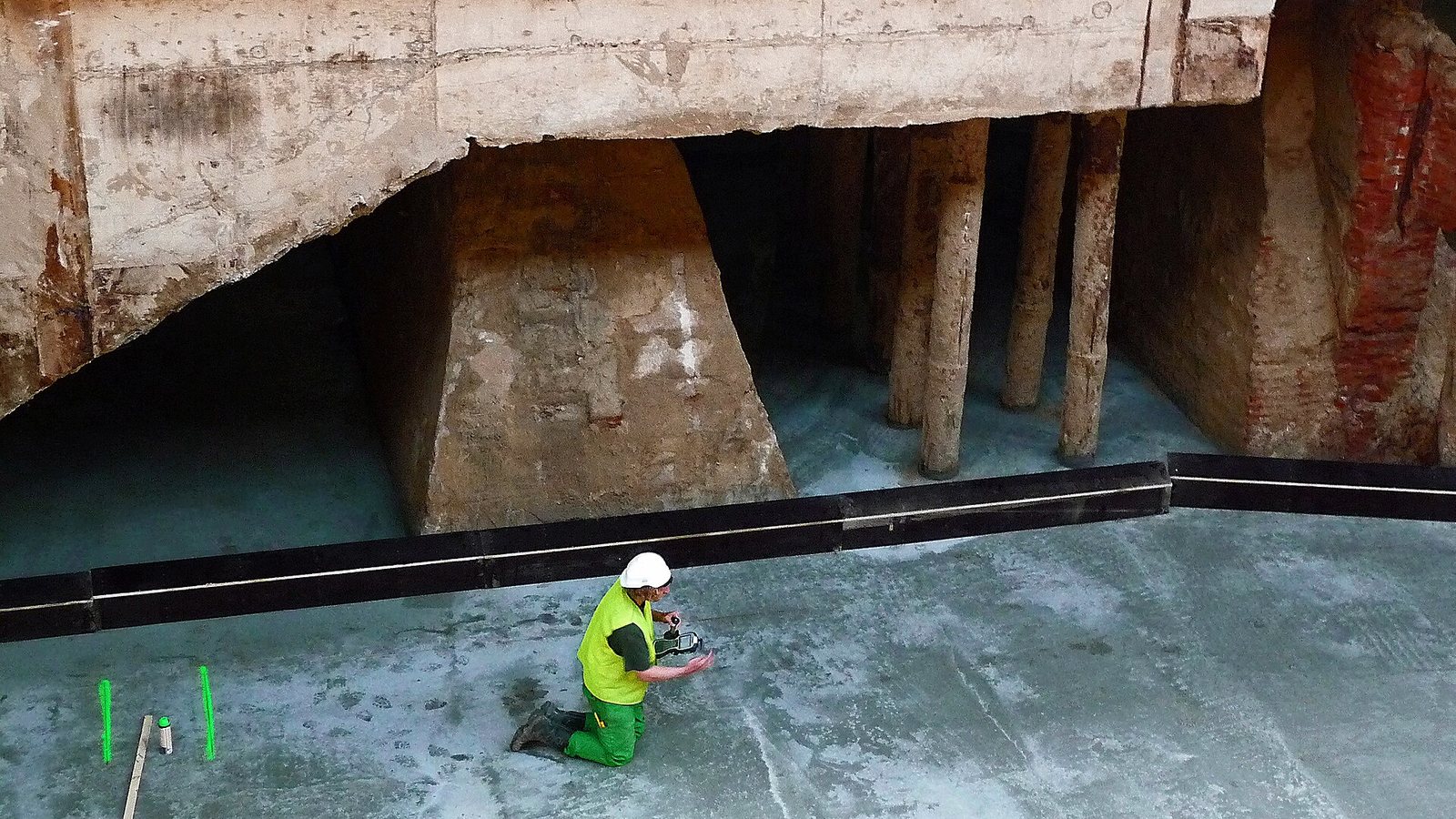 A construction worker in a hard hat working below the foundations during the renovation of Amsterdam Central station