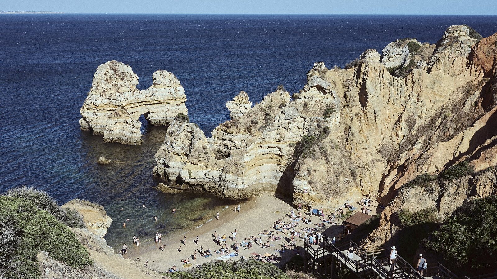Sea stacks and a sandy cove below sandstone cliffs near Lagos in the Algarve, Portugal