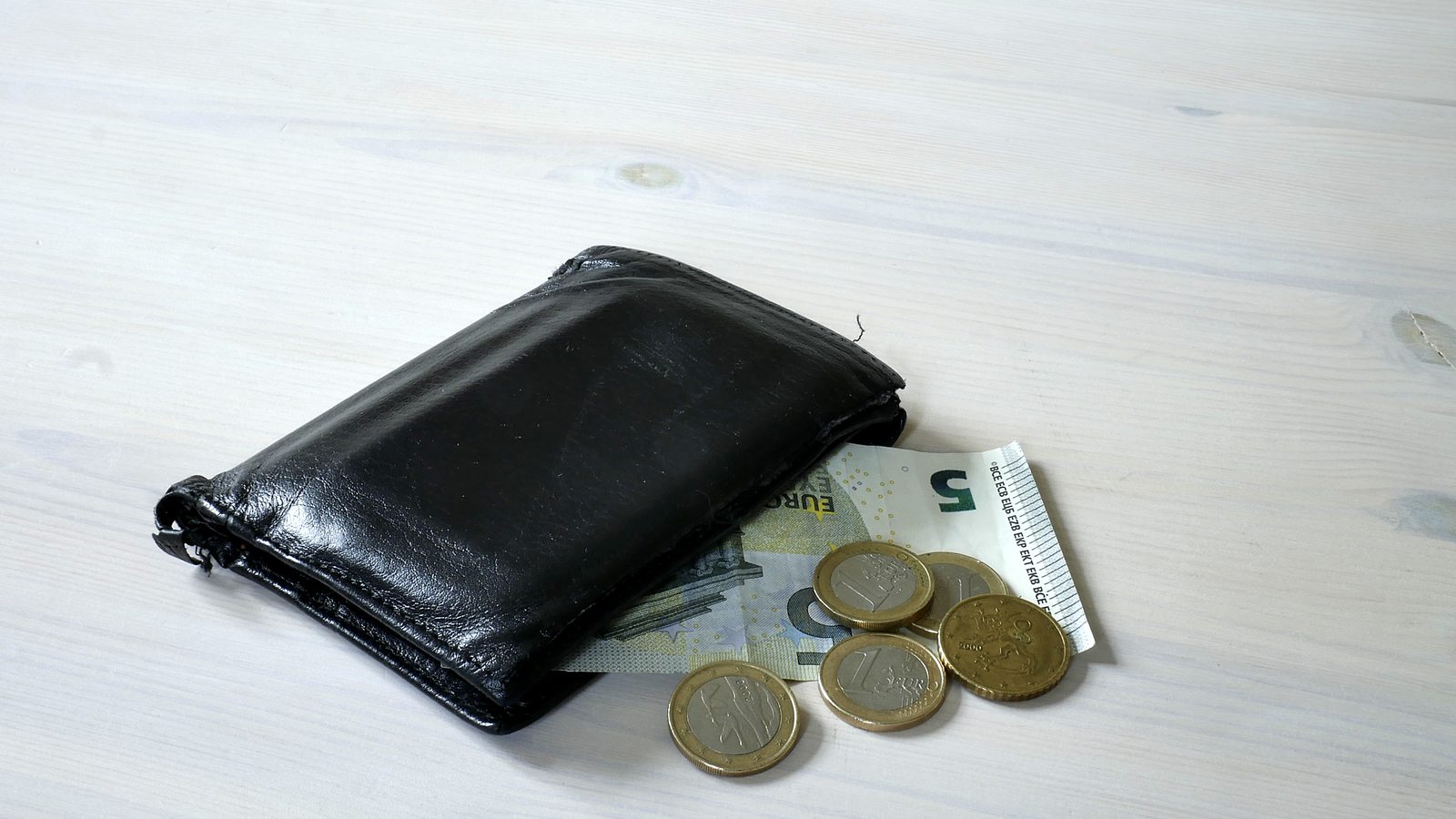A black wallet with euro banknotes and coins