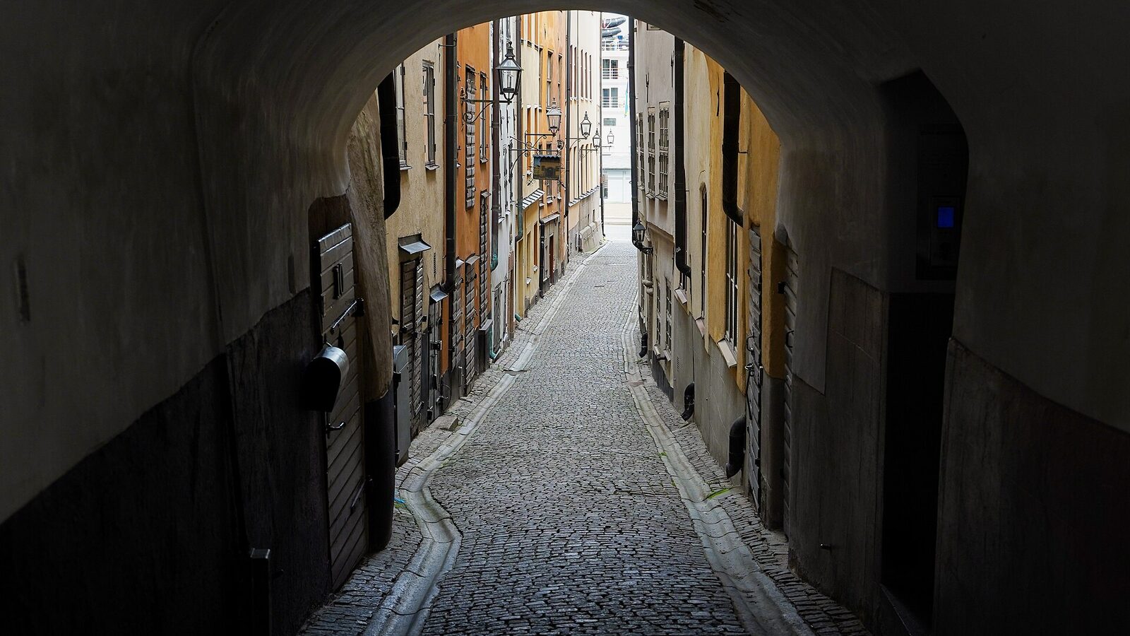 A row of brightly painted houses behind a pedestrian tunnel in an alley in Gamla Stan, the old town of Stockholm, Sweden