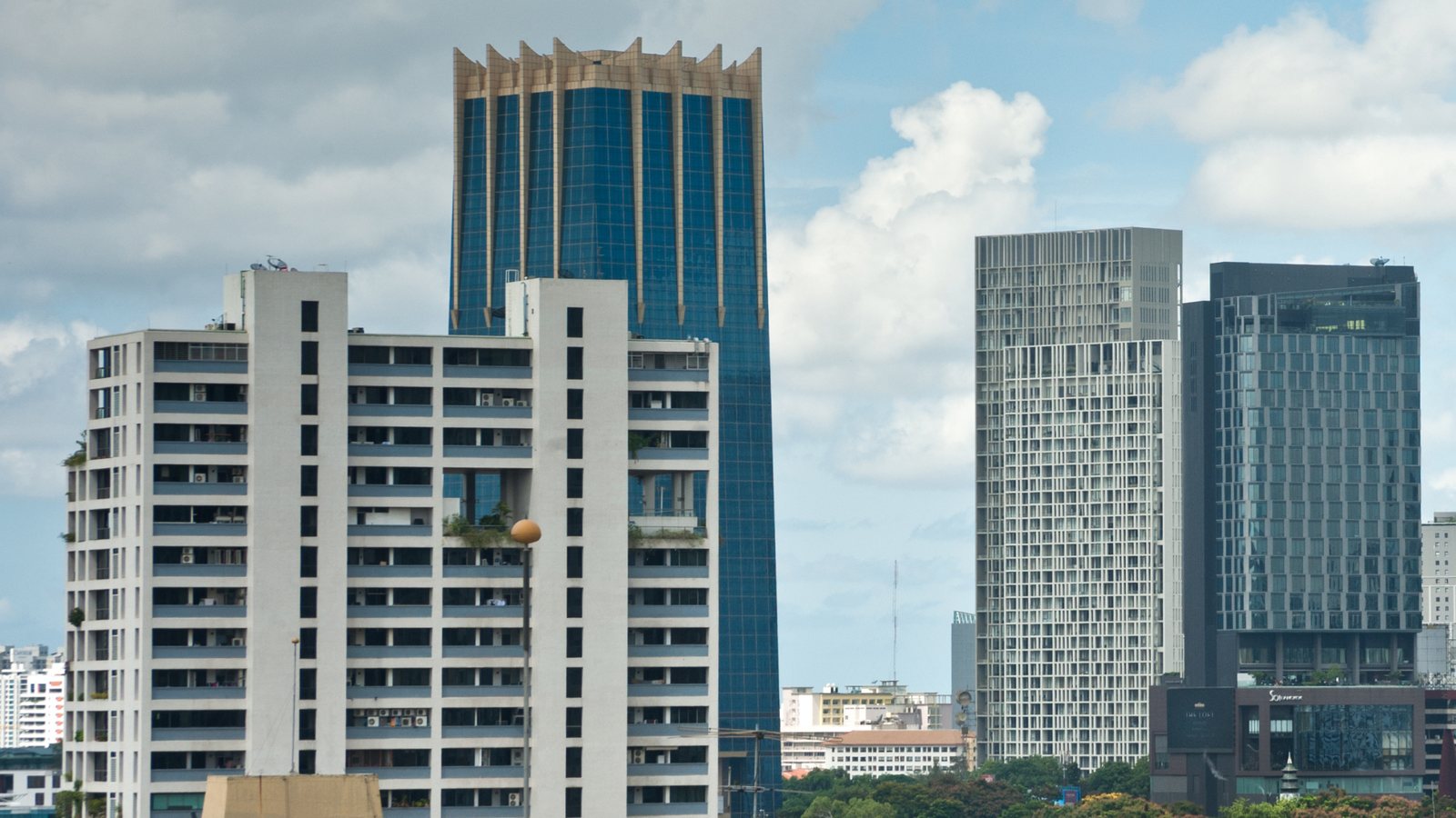 Office and residential towers in central Bangkok under a blue sky with white clouds