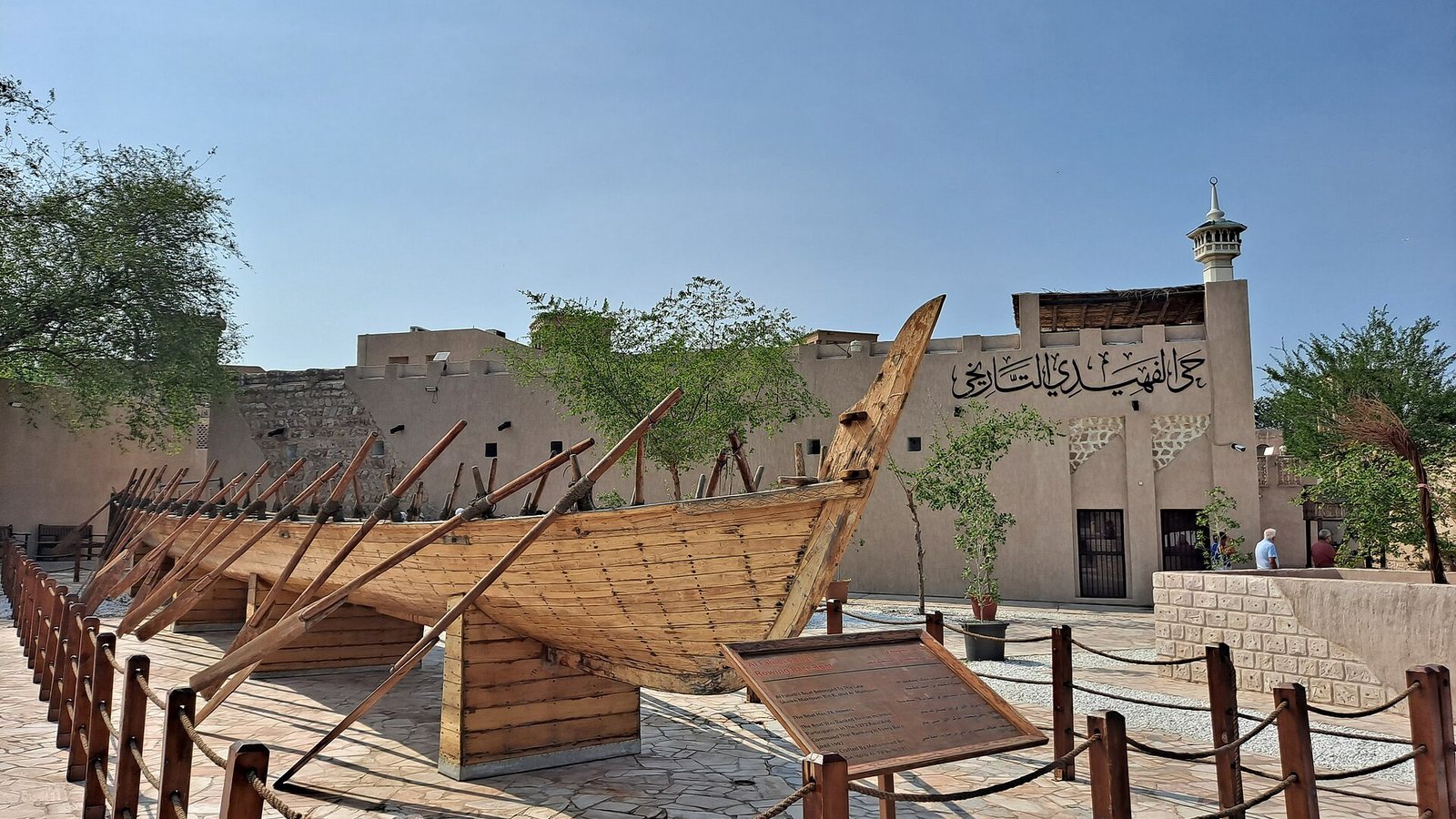 A traditional wooden boat on display in front of sand-coloured buildings in Dubai's Al Fahidi Historical Neighbourhood