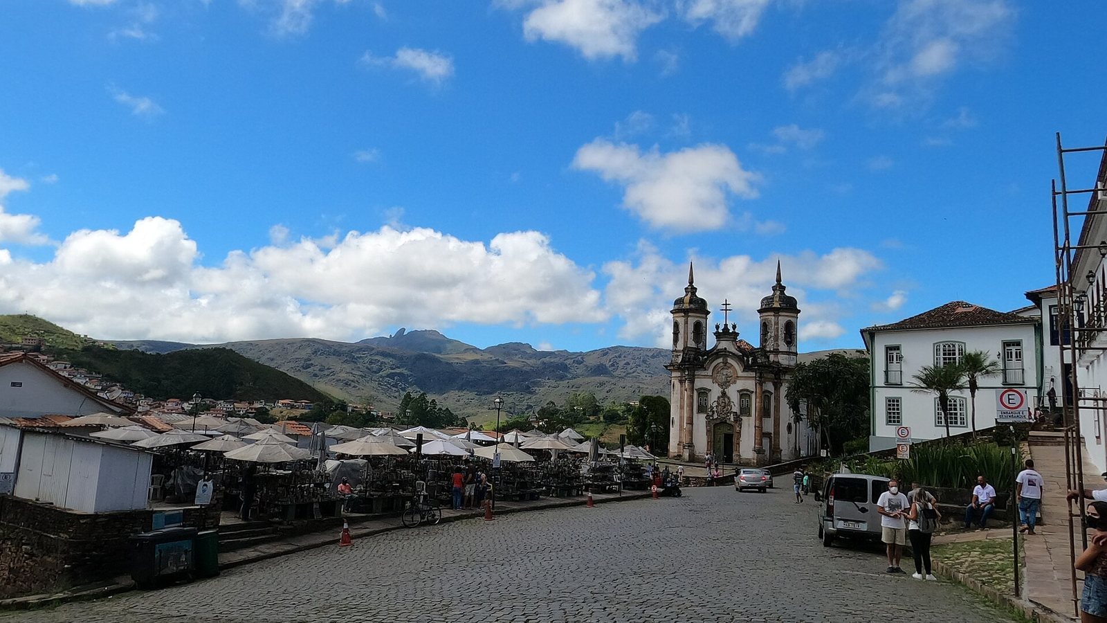 Cobbled square leading to the twin-towered São Francisco de Assis church in Ouro Preto with green hills behind